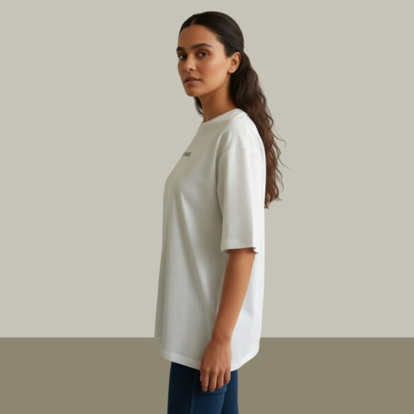 Woman wearing Asome oversized white cotton t-shirt with “Less is More” print on front.