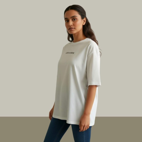 Woman wearing Asome oversized white cotton t-shirt with “Less is More” print on front.